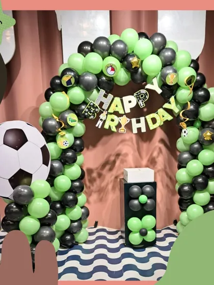 Goal! A super cool football-themed birthday party setup. The black and green balloon arch and giant soccer ball are perfect for any little sports fan.