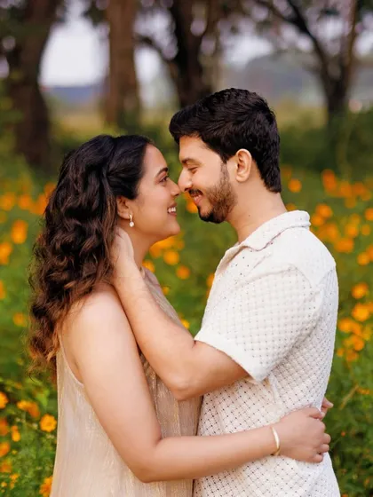 The best pre-wedding photoshoots are the ones filled with genuine smiles. Here, the couple shares a natural, happy moment, styled in comfortable, light-colored clothing perfect for a sunlit outdoor session.