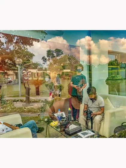 A color version of a reflection at Gallery 1AQ in Delhi, capturing the interplay of clouds, landscape, and human activity. The layers create a complex scene of people interacting with art and their surroundings.