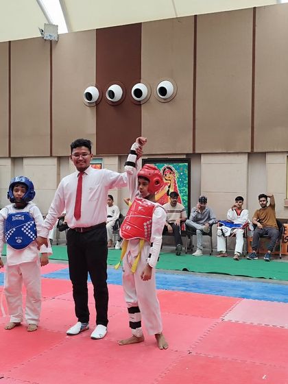 A referee raises the hand of our victorious student at the New Delhi District Taekwondo Championship. This moment captures the culmination of countless hours of training and dedication.