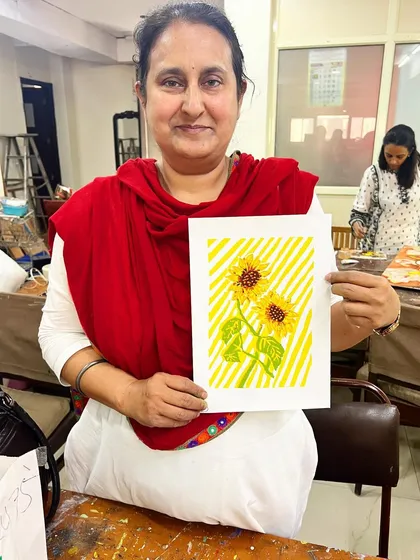 A proud student holds up her finished sunflower silkscreen print. The joy of creating your own print is unmatched.