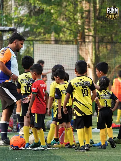 A coach gathers the youngest group for a team talk, explaining the next drill and keeping them engaged.