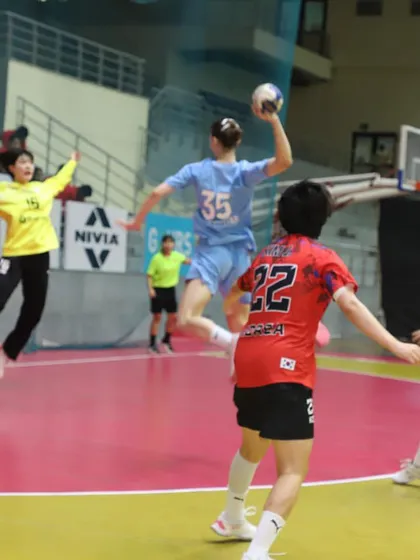 An intense moment of action as a player attempts to score against the goalkeeper in a handball match. The clear view from the stands ensures spectators don't miss a second.
