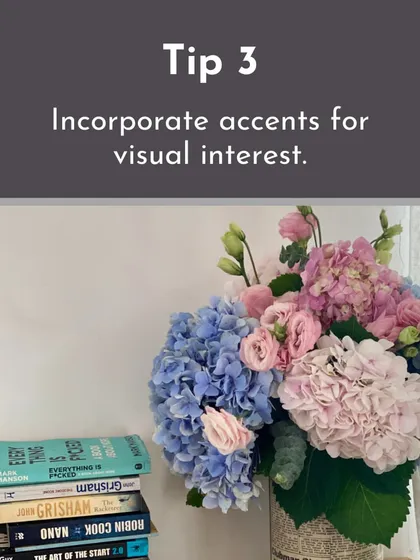 This arrangement of blue and pink hydrangeas next to a stack of books shows how to incorporate floral designs into home decor, using accent colors for visual interest.