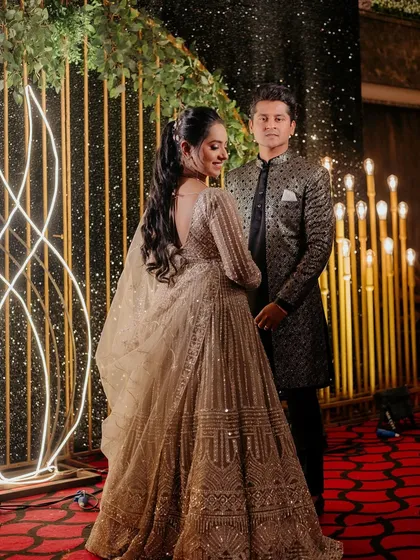 A full-length shot of the couple, showcasing their coordinated and elegant reception outfits.