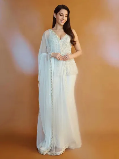 Nora Fatehi looks ethereal in this white peplum and sharara set by Ritika Mirchandani. This is a great example of fusion wear, blending traditional embroidery with a modern silhouette for a chic, celebratory look.