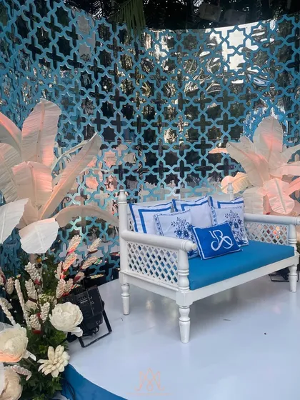 A graceful seating area for the couple, with a custom bench, personalized cushions, and a beautiful blue jali backdrop.