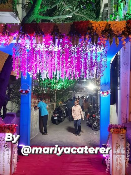 A beautiful entrance arch for an event in Airoli Gaon, with hanging floral decorations and dramatic blue and pink lighting.