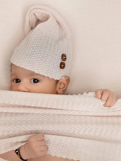 A playful peek-a-boo moment with a newborn under a soft blanket. This shot captures a curious and gentle expression, highlighting the baby's beautiful eyes.