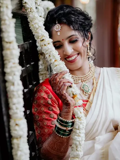 A captivating curly beauty. This portrait showcases a beautiful updo that enhances the bride's natural curls, adorned with a traditional floral garland.