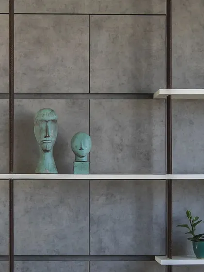 Detail of a shelving system in the 'Acutely Bare' office, where thin white shelves are set against a grid of concrete panels and rebar, blending industrial and minimalist elements.