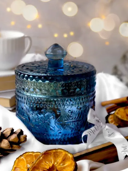 I am happiest when creating eloquent scenes like this. The deep blue of the ornate candle jar is complemented by the warm glow of bokeh lights, dried oranges, and pinecones for a magical winter feel.
