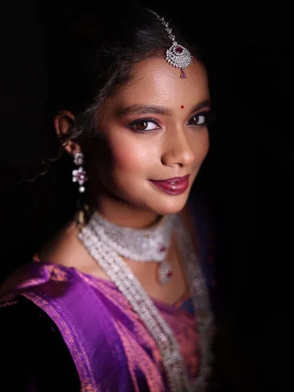 A close-up portrait using low-key lighting to create a moody and elegant feel, focusing on the subject's expression and jewelry.
