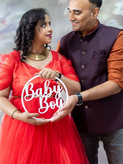 A sweet couple's portrait using a "Baby Boy" prop to share their exciting news.