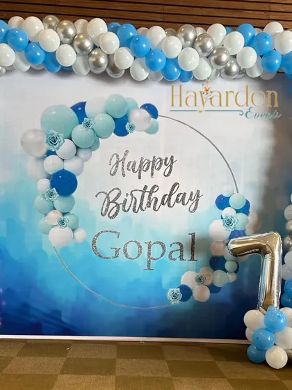 A blue and silver themed 10th birthday party. The decor includes a large printed backdrop and foil numbers.