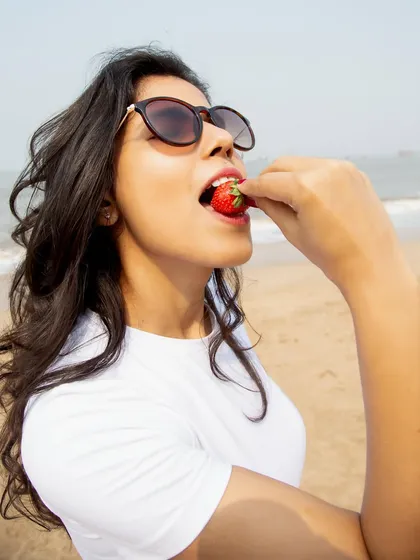This close-up shot of eating a strawberry on the beach is playful and sensory. It's a great example of lifestyle content that feels candid and engaging, perfect for summer campaigns.