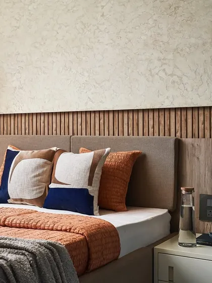 The guest bedroom is designed with neutral tones and a touch of blue for a calm ambiance. The bed wall features a panel of wooden textured flutes and a concrete-finish texture paint.