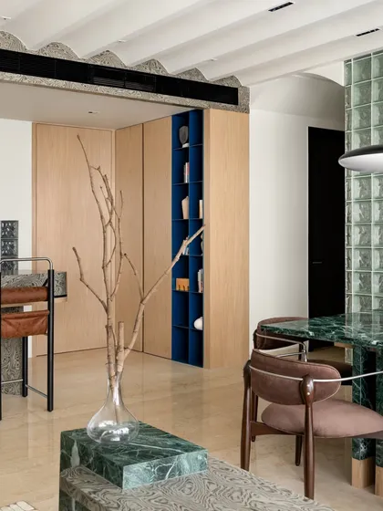 A view from the dining area, showing the connection to the living room and the custom shelving unit. The space is designed to be inclusive and engaging.
