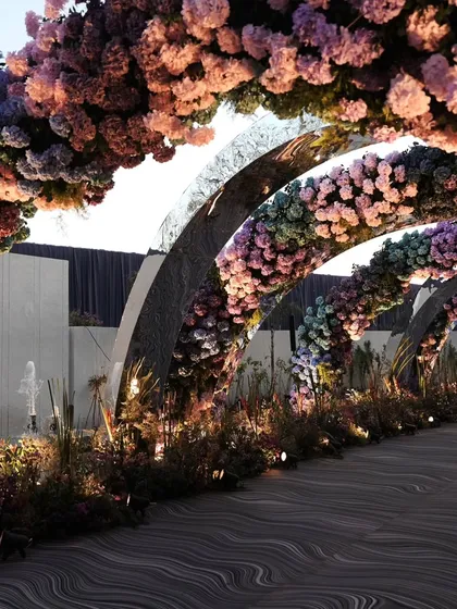 A tunnel of floral arches creates a magical pathway for guests. The gradient of colors and the warm lighting make for a truly enchanting walk.