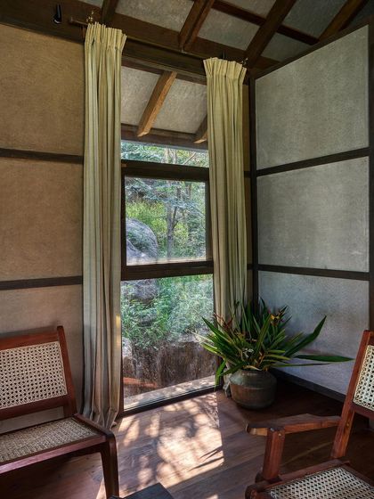 A quiet seating corner in the cottage, where large windows and simple cane chairs invite you to sit and enjoy the view.