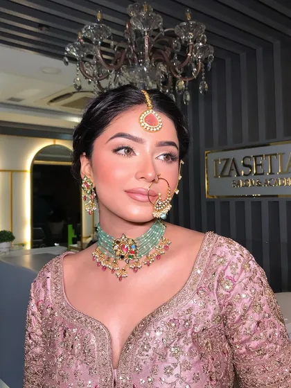 A close-up of the makeup and jewelry that perfectly complement the pastel bridal lehenga. The mint green jewelry adds a beautiful contrast.