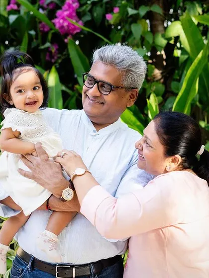 The vibrant colors of the garden background complement the joy in this three-generation portrait. Outdoor settings are wonderful for relaxed family photos.