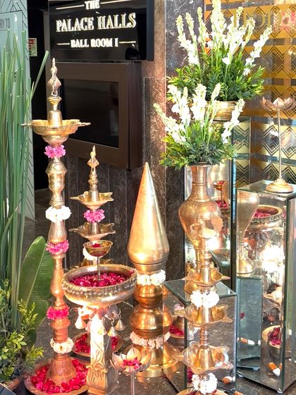 A stunning arrangement of multi-tiered brass lamps (diyas) decorated with flowers, a symbol of light and celebration in Indian festivities.
