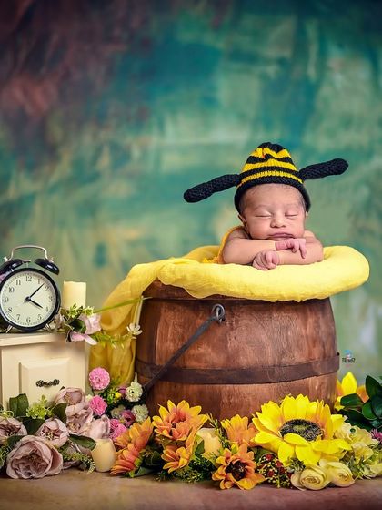A sweet little 'honey bee' theme, with the newborn sleeping in a honey pot. The alarm clock prop adds a whimsical touch.