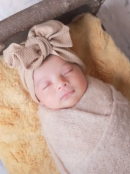 An overhead close-up of the baby in a large bow headband, part of our 'Wooden Era' collection. We have a wide variety of accessories to style your session.
