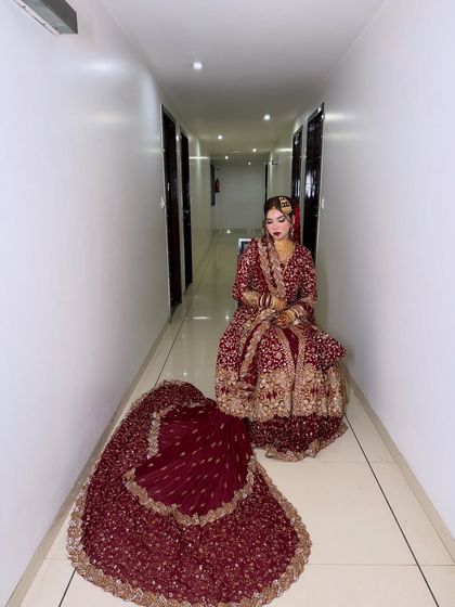 An artistic shot of bride Tannoo in a hotel hallway, with her beautiful maroon lehenga spread out. The look is both dramatic and elegant.