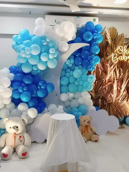 Another angle of the blue and white baby shower setup, highlighting the "Oh Baby" neon sign against a backdrop of golden dried palms for a touch of boho chic.