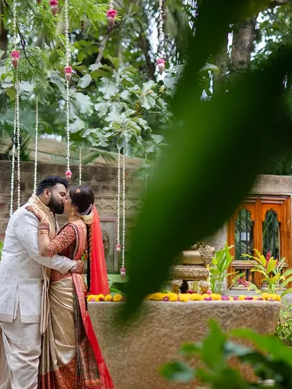 A stolen kiss, partially obscured by leaves, gives this photo a candid and intimate feel, as if capturing a private moment.