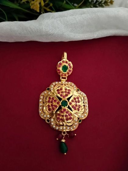 A restocked favourite, this Jadau pendant features a floral design with red and green stones. It's a versatile piece that can be added to any gold chain.
