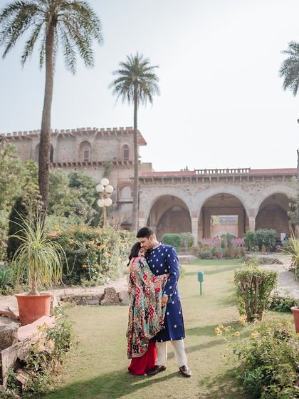 A romantic embrace in the gardens of Fort Tijara, with the historic palace creating a grand and timeless backdrop.