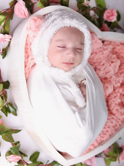 A close-up shot focusing on the baby's face within the rose-filled heart bowl, creating a soft and intimate portrait.