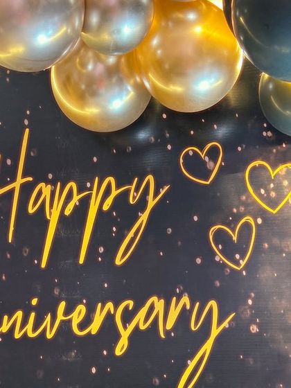 A close-up of the 'Happy Anniversary' neon sign against a sparkling black backdrop, adding a personalized and warm glow to the celebration.