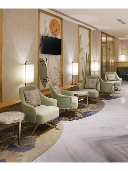 A wide view of the main lounge at the 'Reserved Lounges' in Bangalore. The layout uses curved seating arrangements and custom rugs to define different zones within the larger open space, guiding flow and creating pockets of privacy.