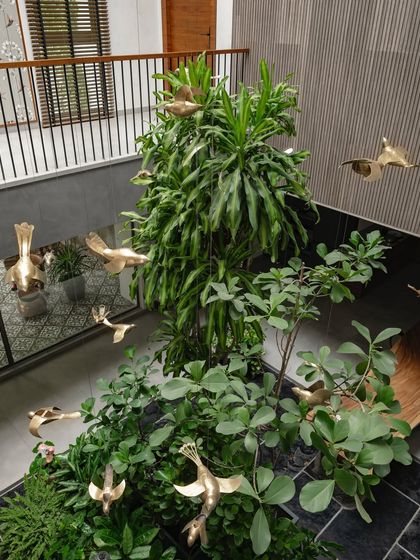 An interior courtyard featuring custom-made brass bird sculptures that appear to fly through the space. These artistic elements add a sense of movement and magic to the biophilic design.