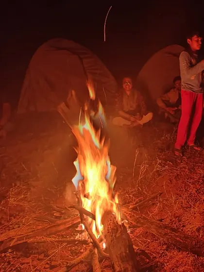 The campfire glowing in the dark, with trekkers sitting around and enjoying the warmth and conversation.