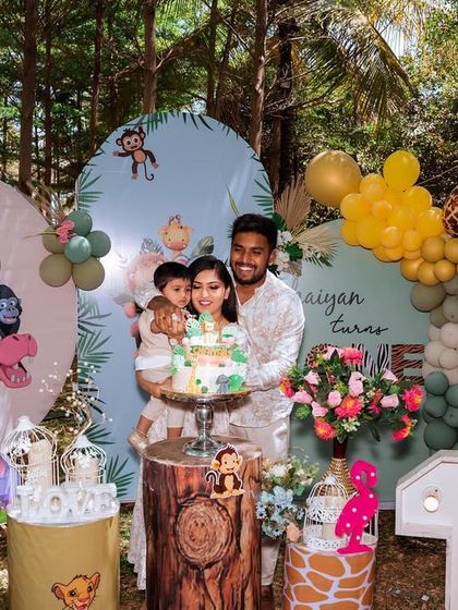 A happy family celebrating their little one's first birthday with our jungle theme decor. We used custom backdrops with cute safari animals, wood-textured pedestals, and a marquee number '1' to complete the look.