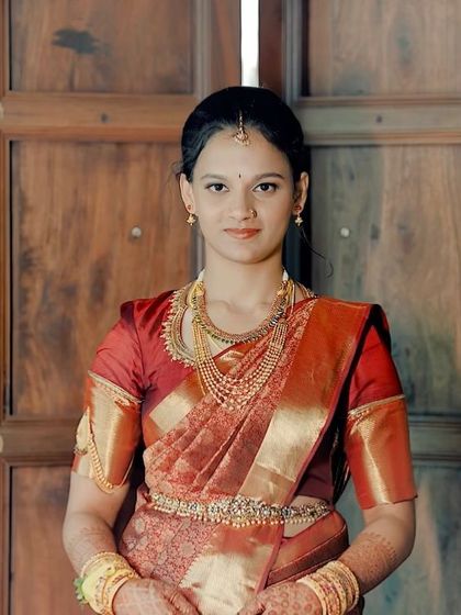 A classic portrait of the bride in her red engagement saree. The makeup is traditional and elegant, with a focus on her expressive eyes.
