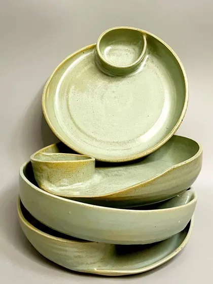 A stack of my green glazed chip-and-dip platters. The way they stack shows their consistent form, while the unique glaze on each piece highlights their handmade quality.