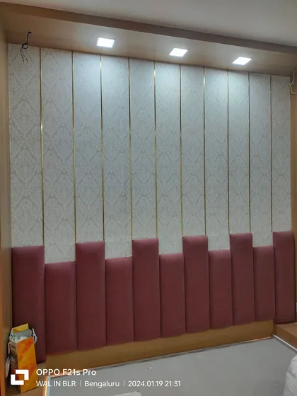 For this bedroom, I created a floor-to-ceiling upholstered wall. The design mixes a patterned wallpaper with vertical panels, slim gold metal inlays, and a soft pink padded base for a complete, luxurious headboard wall.