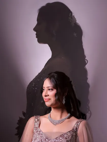 A creative double-exposure style portrait. The bride's silhouette is cast as a shadow behind her, creating a thoughtful and artistic image that is truly unique.