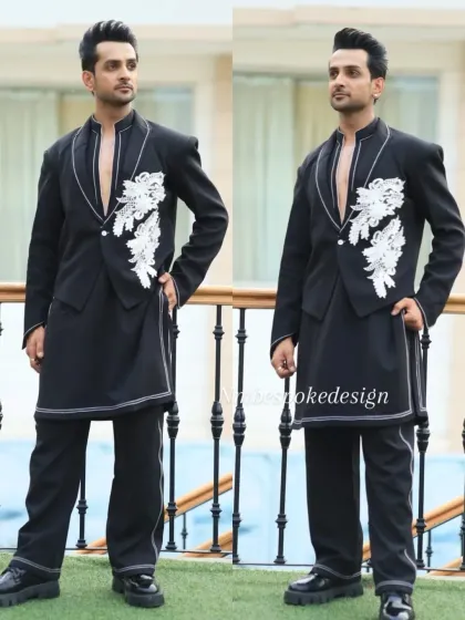 A modern, edgy take on the waistcoat. This black open-front piece is layered over a longline kurta and features white floral appliqué and contrast stitching.