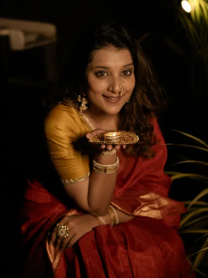 A personal photo from my own Diwali celebration. I am wearing a classic red and yellow silk saree, styled with traditional jewelry and a simple diya, capturing the warm spirit of the festival.
