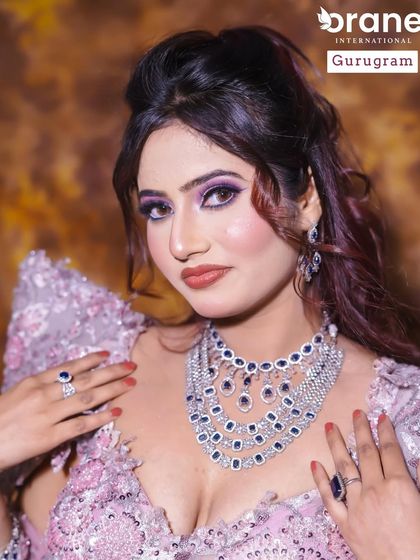 This student's work features a stunning layered necklace and dramatic purple eye makeup. It shows a great understanding of how to balance bold accessories with equally bold makeup.