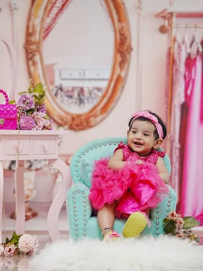 A change of outfit into a vibrant pink dress, this little girl is all smiles during her six-month photoshoot.