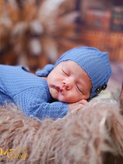 A close-up portrait of the sleeping newborn. The focus is entirely on his serene face and the soft textures of the hat and blanket.
