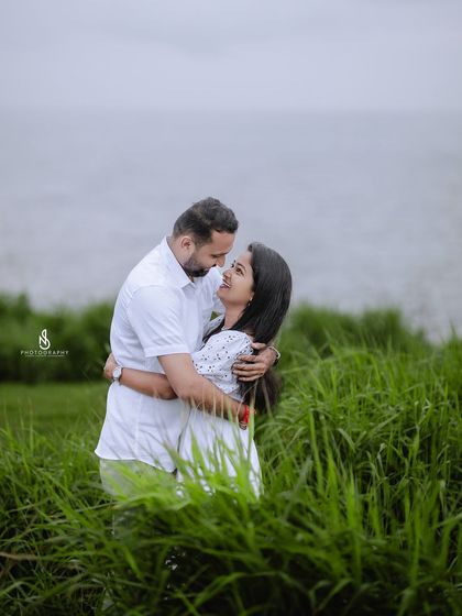 An intimate embrace, capturing the deep connection between the couple against the soft, grey sky and sea.